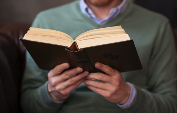 一个穿绿色毛衣的人在看书图片下载