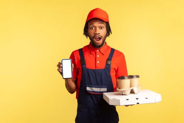 拿着黑屏智能手机、披萨和外卖咖啡的快递员lue工作服。图片下载