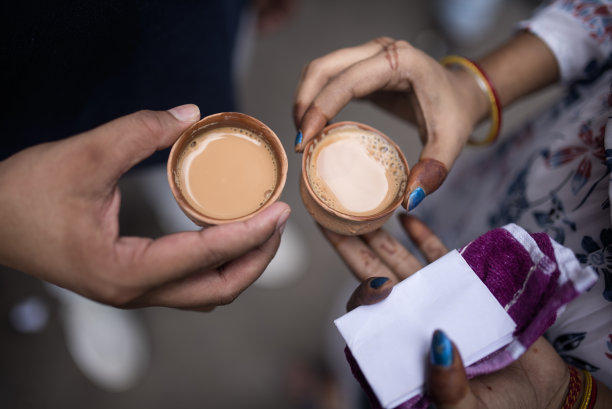 一对可爱的情侣在加尔各答的街道上喝茶，手拿茶壶的特写照片在街上的茶摊Stock photo图片下载