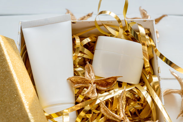 圣诞礼物与美容化妆品产品和装饰在一个金色的礼品盒。节日的概念。无品牌包装为您的设计图片下载