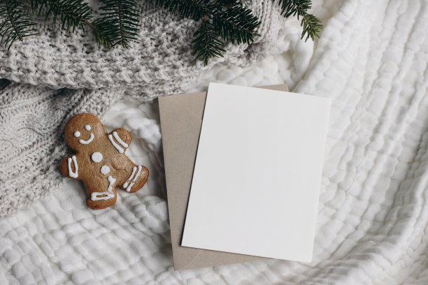 圣诞节的静物画。空白贺卡，邀请模型与工艺信封。、姜饼人饼干和冷杉树枝。白色细布台布，床罩。Flatlay顶视图。寒假。图片下载