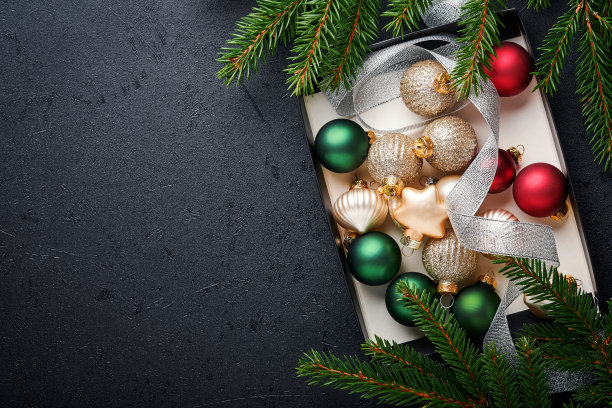 圣诞金色，红色，绿色和银色的球在黑色背景的盒子里。圣诞装饰。用金饰的节日装饰品。边界设计。前视图。圣诞贺卡。图片下载