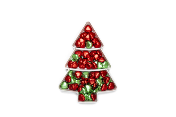 心形巧克力糖果放在松木形状的盘子上，还有圣诞装饰。图片下载