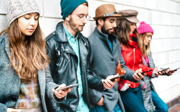 使用智能手机的千禧一代男孩和女孩的侧面-沉迷于智能手机的人-总是连接青少年的生活方式概念-生动的过滤器，重点放在第一个左边的手机图片下载