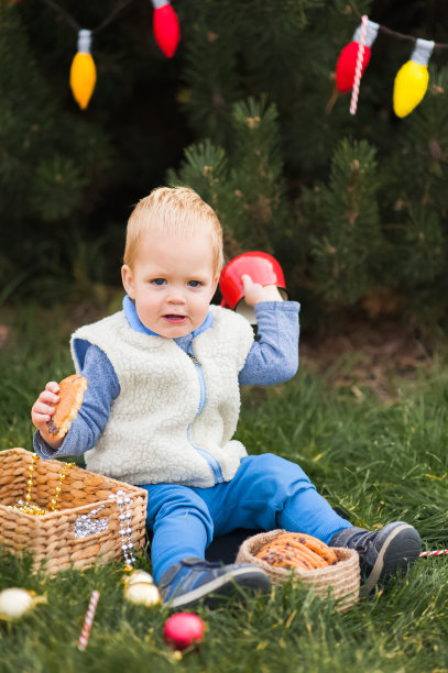 可爱的蹒跚学步的孩子在装饰过的后院吃着牛奶曲奇饼。图片下载