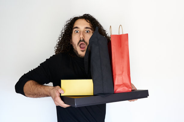 黑色星期五促销的概念，年轻惊讶的男人拿起他所有的购物袋和包裹图片下载