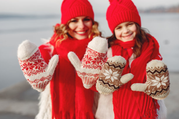 母亲和孩子戴着针织的冬季帽子在冬季公园玩耍图片下载