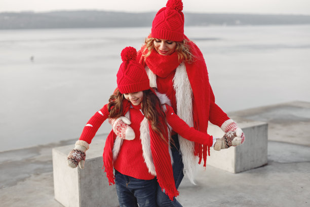 母亲和孩子戴着针织的冬季帽子在冬季公园玩耍图片下载