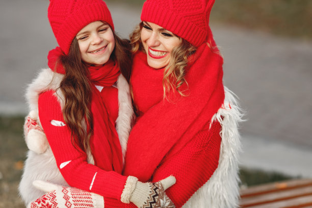 母亲和孩子戴着针织的冬季帽子在冬季公园玩耍图片下载