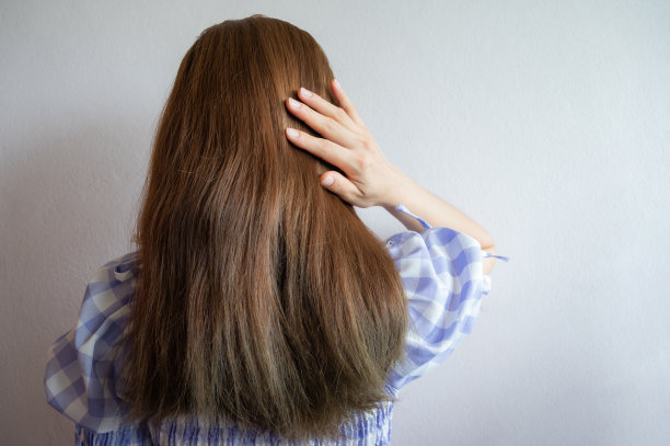 亚洲女人的后视图，站着抚摸她浓密的头发。图片下载