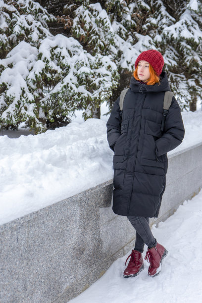 冬天，一个穿着休闲装的少女走在白雪覆盖的城市街道上。一位在城里度周末的年轻女士。都市假期，寒假，慢生活。时尚的服装，青春的时尚图片下载