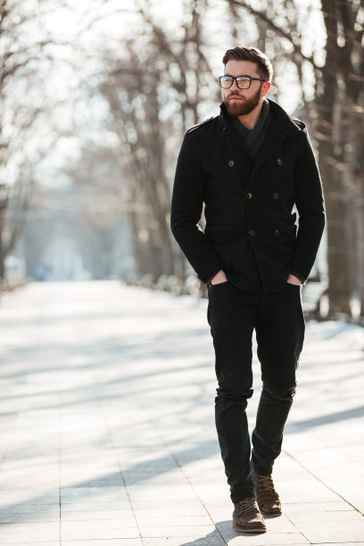 一个迷人的年轻人在冬季公园散步图片下载