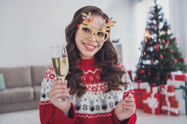 照片中，可爱开朗的卷发女孩戴着有趣的眼镜庆祝除夕精神在工作场所的白色室内图片下载