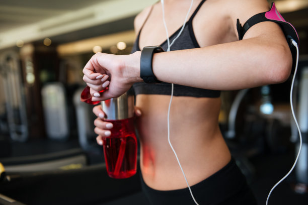 裁剪的照片，年轻的运动女人看手表。图片下载