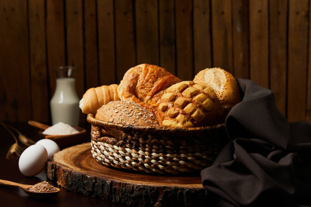 木制背景的面包篮和桌子上的牛奶，鸡蛋，面粉和麦穗。食品和烘焙概念。水平的照片。图片下载