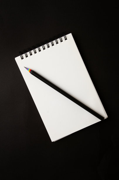 黑色简单的铅笔，五颜六色的刨花，彩虹的颜色，白色的笔记本上有一个弹簧，黑色的背景，没有人，图片下载