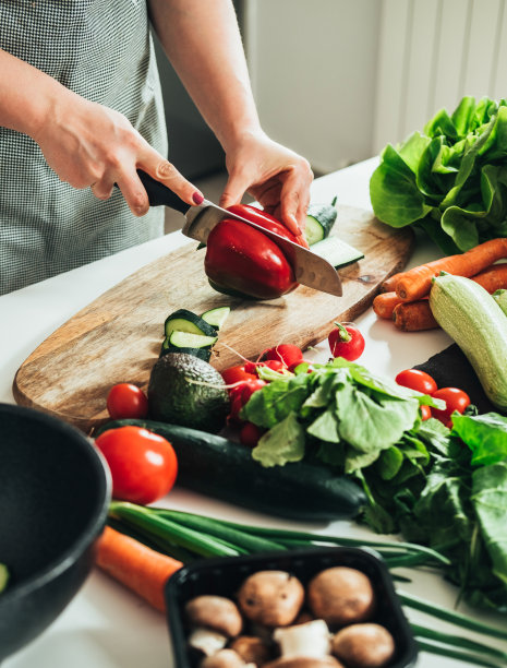 女人在厨房餐桌上切新鲜蔬菜的特写照片图片下载