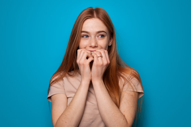 时尚女性的蓝色背景肖像。孤立的白色。漂亮的年轻女人。手的姿势。有雀斑的姜黄色女人做着许愿手势。图片下载