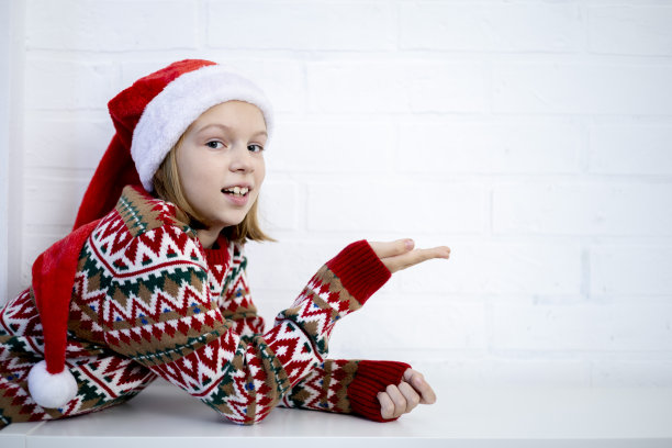 女孩穿着针织毛衣，戴着圣诞老人的帽子。假期健康概念。图片下载