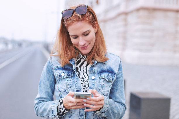 年轻的红发女子在户外用智能手机发信息图片下载