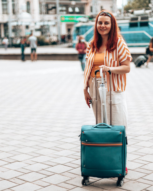 年轻的白人女孩穿着时髦的衣服，拿着智能手机和旅行行李站在车站等火车图片下载