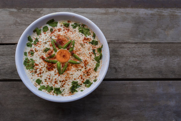 Raita印度配菜酸奶含有切碎的黄瓜或其他蔬菜，和香料顶部视图照片上的木制背景股票照片图片下载