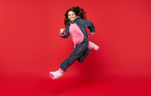 快乐的孩子穿柔软的睡衣。完整的长度。孩子穿着舒适的睡衣跳起来。甜蜜的梦想。图片下载