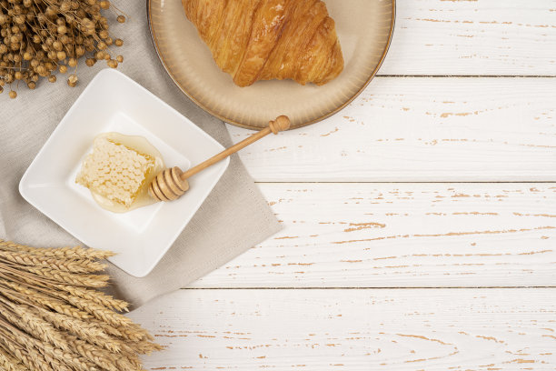 早餐是牛角面包，餐桌上有牛角面包，蜂窝。干燥亚麻植物与小麦植物图片下载