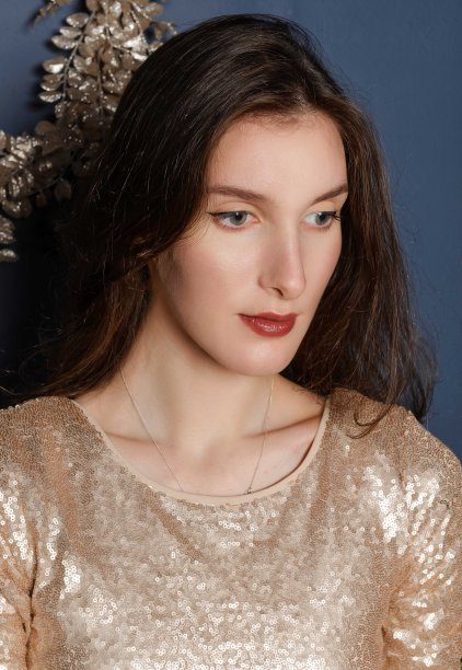 深色皮肤的白种人女孩穿着金色的裙子，近身肖像向下看图片下载