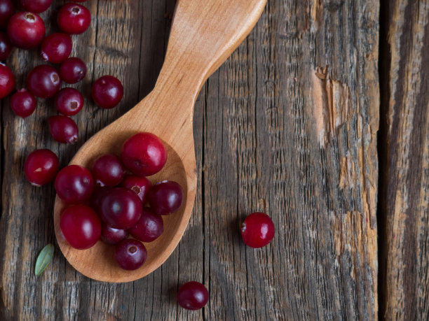 熟的新鲜蔓越莓放在木勺里，放在一张旧木桌上图片下载