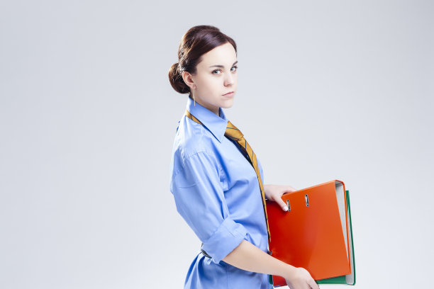 人们在商业。自信年轻的黑发白人女商人在官方蓝色衬衫和领带与文件夹堆摆姿势。水平图像组成图片下载