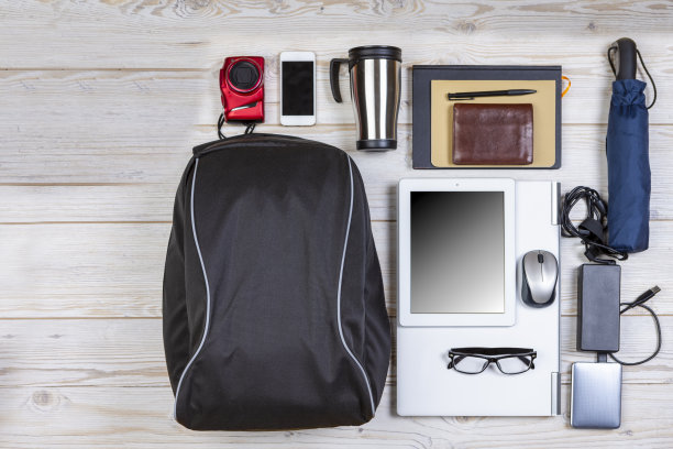 平了的概念。Top View Flat Lay背包与笔记本电脑和平板电脑附近，移动电话与笔记本电脑和配件在木制背景。旅游生活配件的概念图片下载