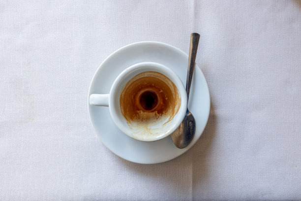 空的白色咖啡杯和勺子放在盘子上，桌上铺着白色的桌布图片下载