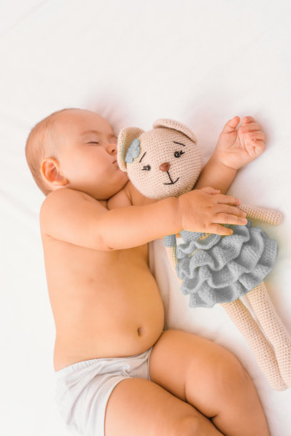 一个婴儿和他最喜欢的针织玩具猫睡觉，垂直照片。选择性地关注玩具图片下载