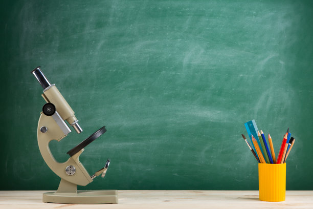 教育理念——大礼堂课桌上放显微镜，黑板为背景图片下载