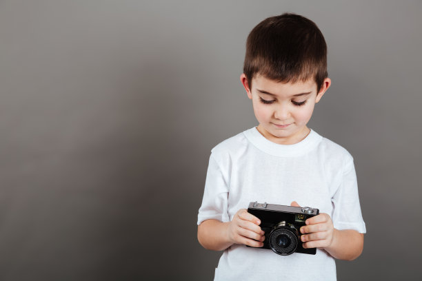可爱的小男孩拿着相机，用着相机图片下载
