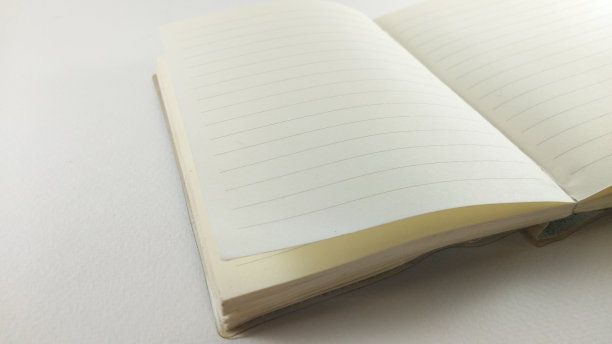 乳白色的笔记本在中间展开。在桌子上放一个斜角。图片下载