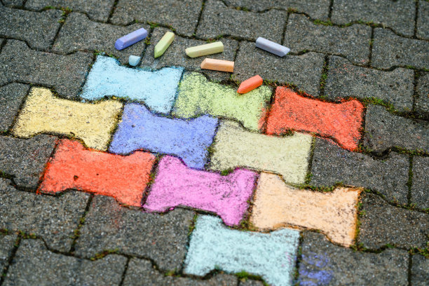 在后院的地面上用彩色粉笔画着人物。儿童活动，绘画和创作图片。夏季创造性的户外活动。图片下载