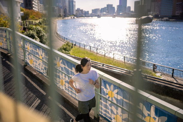 一个女人在城市的河边慢跑图片下载