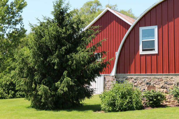 圆形的乡村屋顶，红色的农场石头地基，谷仓，谷仓，绿色的草坪，庭院的建筑背景图片下载
