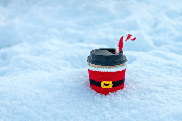 一杯咖啡，圣诞老人的针织衣服和糖果拐杖在冬天新鲜的雪图片下载