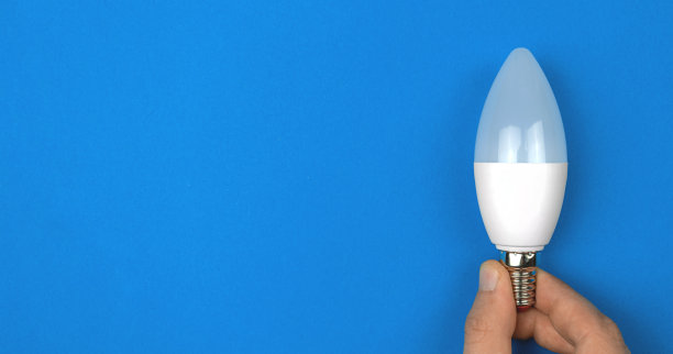 现代环保LED灯泡在手，蓝色背景。横幅，平铺，俯视图，复制空间照片图片下载
