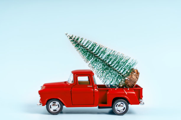 一辆玩具车的蓝色背景上有一棵圣诞树。这是新年和圣诞节气氛的绝佳背景。图片下载
