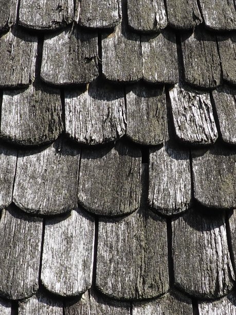 屋顶瓦作为传统的农村屋顶覆盖。瓦片锐角交叉板屋顶块材料的特写。古代工匠——木匠的木制建筑。自然背景。图片下载