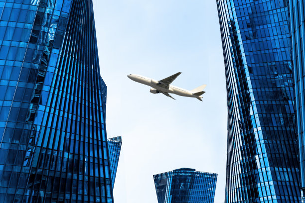 飞机飞过市中心的现代摩天大楼。图片下载