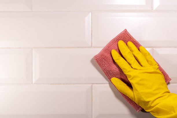 用黄色橡胶手套用粉红色的布擦拭瓷砖表面。厨房消毒图片下载
