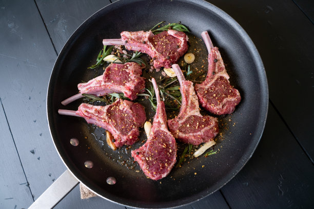 生羊排在煎锅上，配上迷迭香和其他香草图片下载