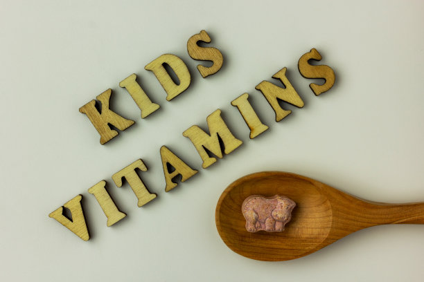 儿童的维生素在白色的木勺的背景。图片下载