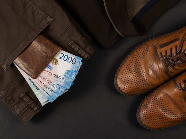 俄罗斯的钱。特写一个装满1000和2000卢布钞票的皮夹。男士的鞋子和牛仔裤放在黑色的背景上。钱在你的皮夹里。图片下载