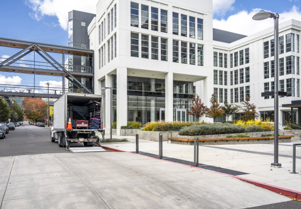 大型半挂车与敞开式箱拖车卸载货物的客户搬到一个新的多层公寓在城市城区图片下载